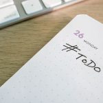 Close-up of a to-do list next to a computer keyboard on a desk.