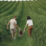 Happy family walking together through a lush green field enjoying nature and togetherness.